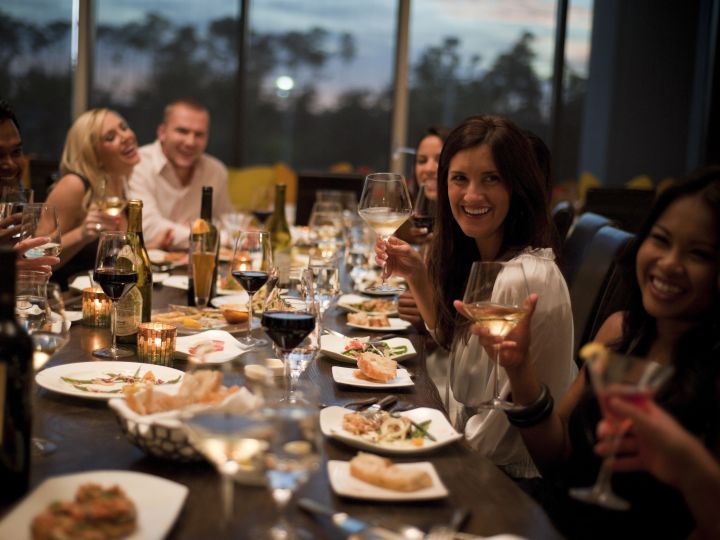 People sitting at long table with food and wine