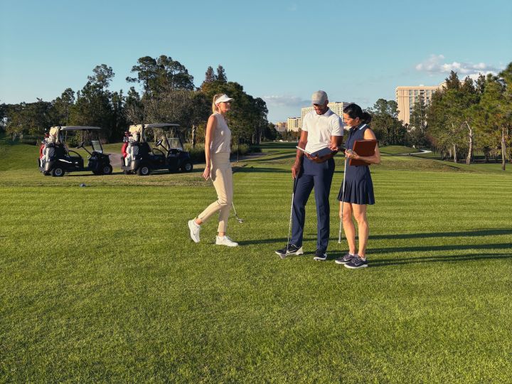 Un homme et deux femmes sur un parcours en or, avec des poussettes en arrière-plan