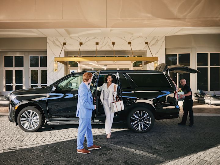 Femme sortant de la voiture souriante. Sa porte s'ouvre alors que le membre du personnel est à la jonction