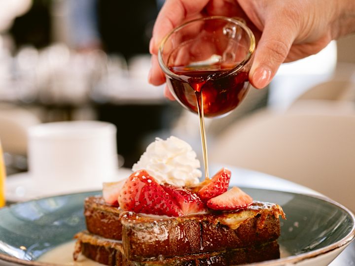 person pouring syrup over food