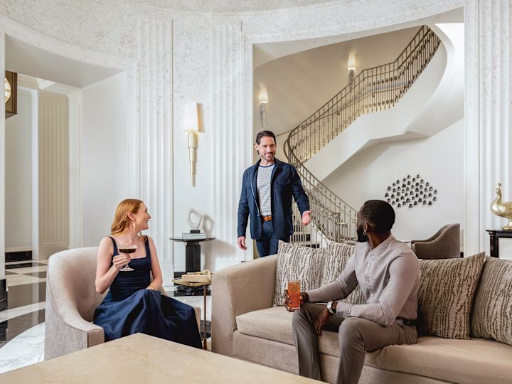 Man and woman sitting in comfortable lobby as another man approaches