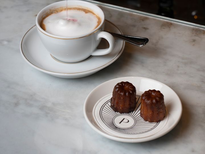 一杯咖啡以手沖泡奶油，並在孔雀小��以碟子盛放甜食