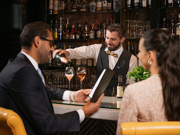 Barman servírující nápoje páru v baru Peacock