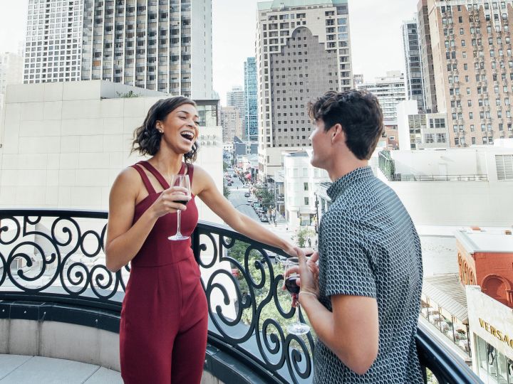 Femme et homme parlant sur le balcon avec du vin à portée de main