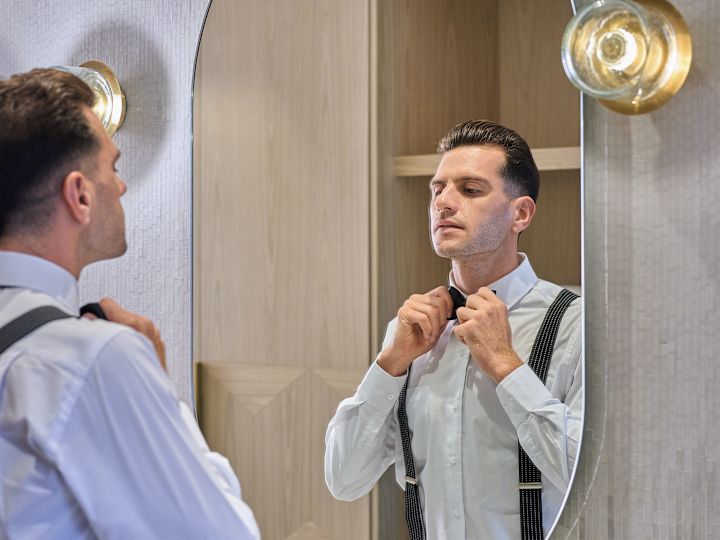 groom looking in the mirror, putting on a tie