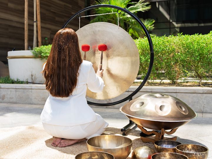 Women hitting gong with mallets outside
