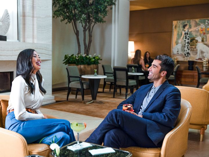 Man and woman smiling as they relaxing in comfortable lobby seating area