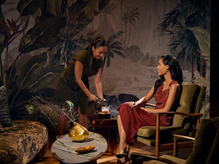 Woman sitting in restaurant area as wait staff member pours drink