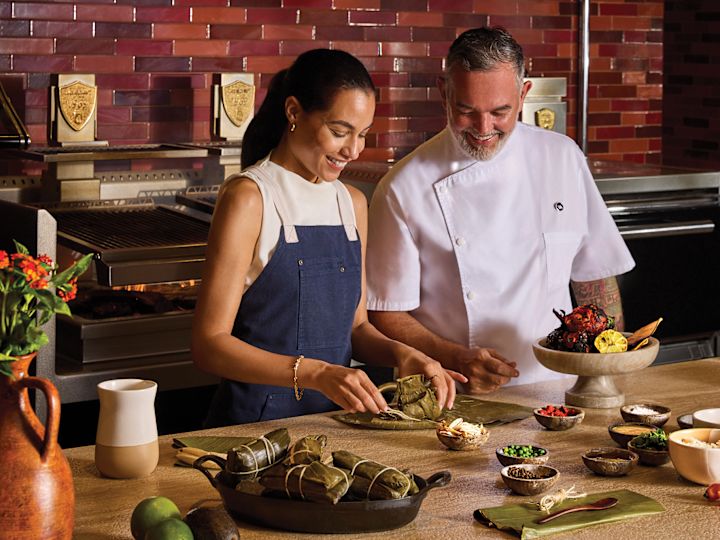 Femeie care zâmbește în timp ce bucătarul șef predă la clasa de gătit