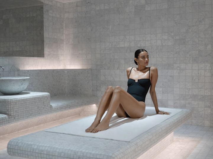 Uma pessoa sentada em uma sala de spa azulejada preparando-se para um banho de vapor de banho turco.
