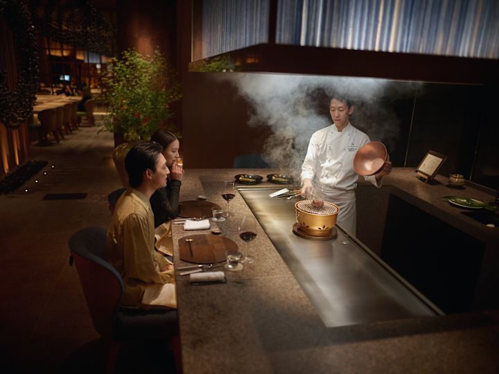 A couple having teppenyaki at Tsukimi prepared by a chef across the hot grill.