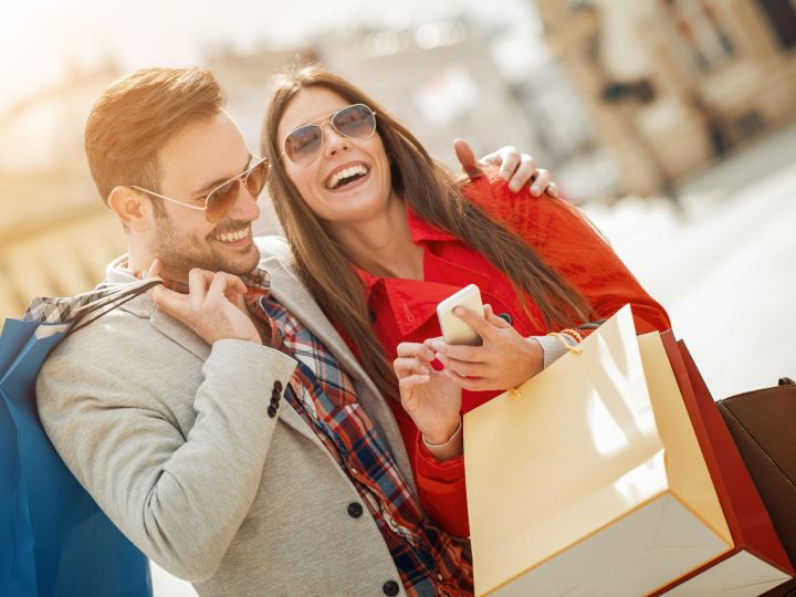 Uomo e donna che ridono insieme e tengono in mano le borse della spesa