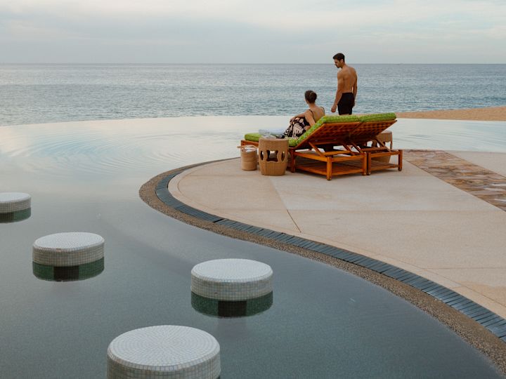 Cuplu relaxându-se în zona piscinei, cu vedere spre ocean