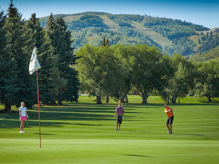 People Playing Golf in an Area with Mountains
