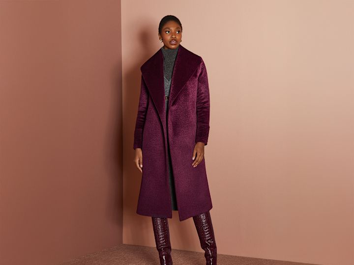 Kvinna som bär en röd kappa och stövlar poserar för en bild