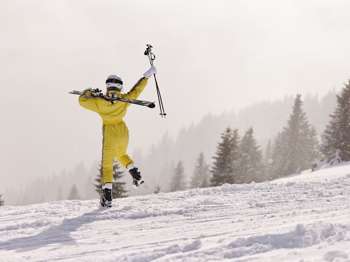 O persoană purtând un costum galben de schi în munți