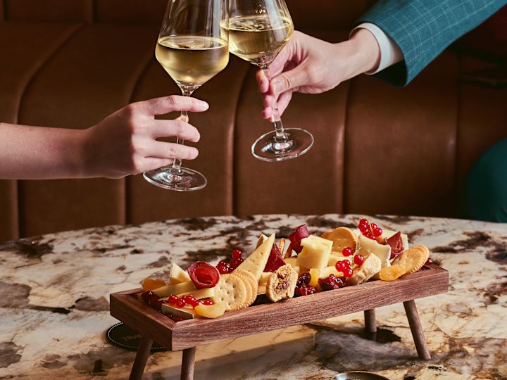 People cheering glasses of wine over a platter of food