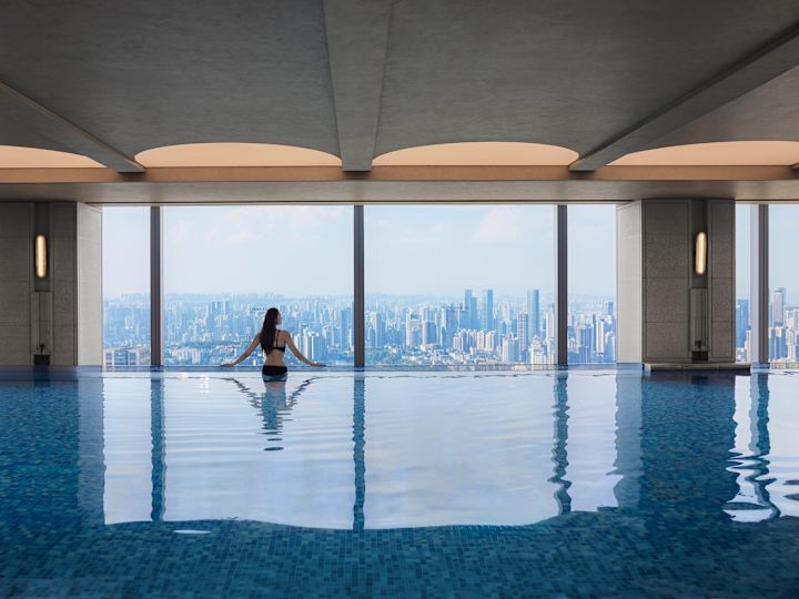 Woman in indoor pool looking out at panoramic city view