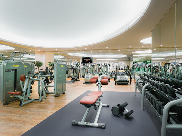 Suuri kuntosali, jossa on painoja, juoksumattoja ja muita moderneja kuntoiluvälineitä