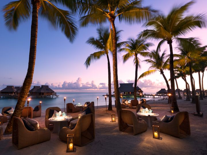 Outdoor Patio Area with Armchairs, Tables and Palm Trees at Dusk