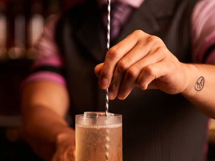 Bartender stiring a cocktail in a tall glass