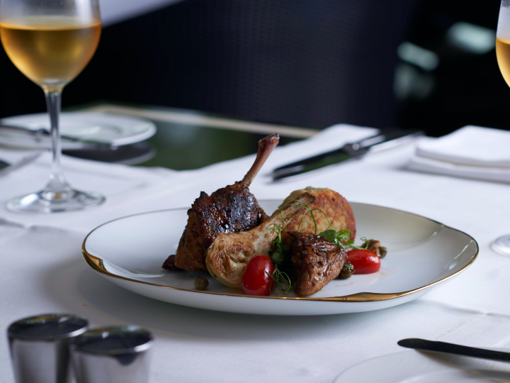 Sweet & sour cherry glazed Duck leg on a white with gold trim plate