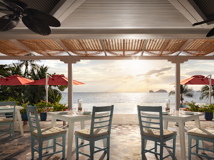 Área de comedor del restaurante Azure con vista al mar al atardecer