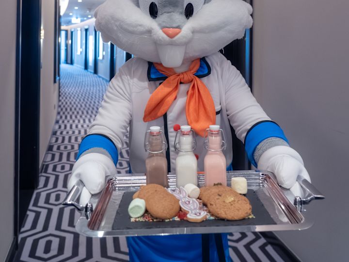Eine in einem Buggs Bunny-Kostüm gekleidete Person liefert Milch und Kekse auf ein Zimmer