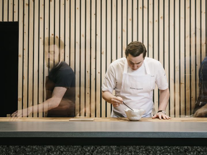man in apron stirring in a bowl
