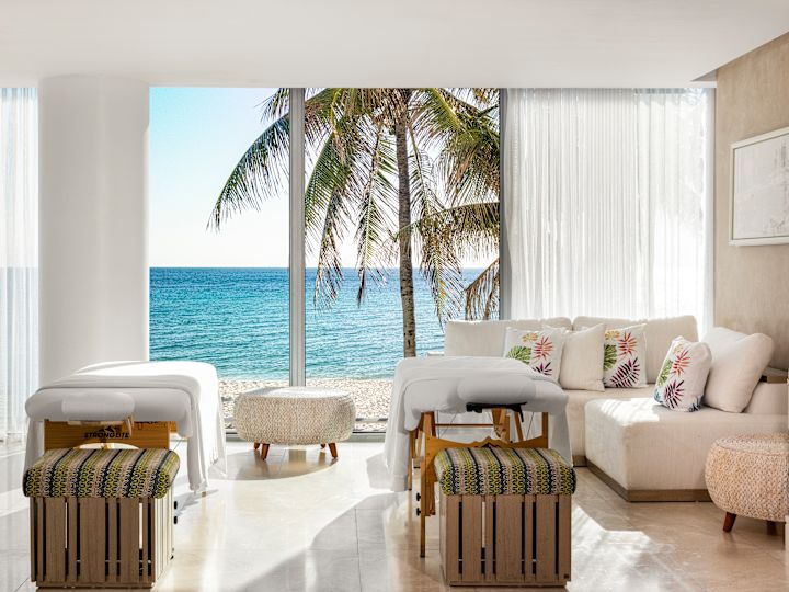 Spa treatment room with massage tables overlooking a view of the ocean