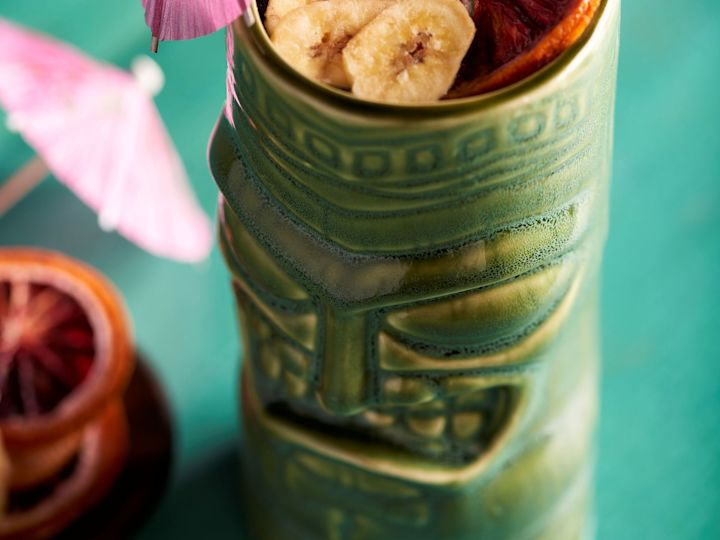 カクテル・セラミック・カップ、バナナ、シトラスフルーツ、カラフルな紙傘のテーブル