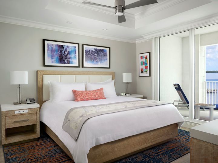 Tempat tidur dalam kamar dengan karya seni di dinding, lampu, dan balkon