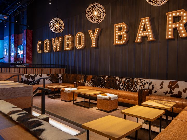 PBR 카우보이 바 인조 소가죽 벤치 스타일 소파와 작은 테이블이 있는 부드러운 좌석 공간.