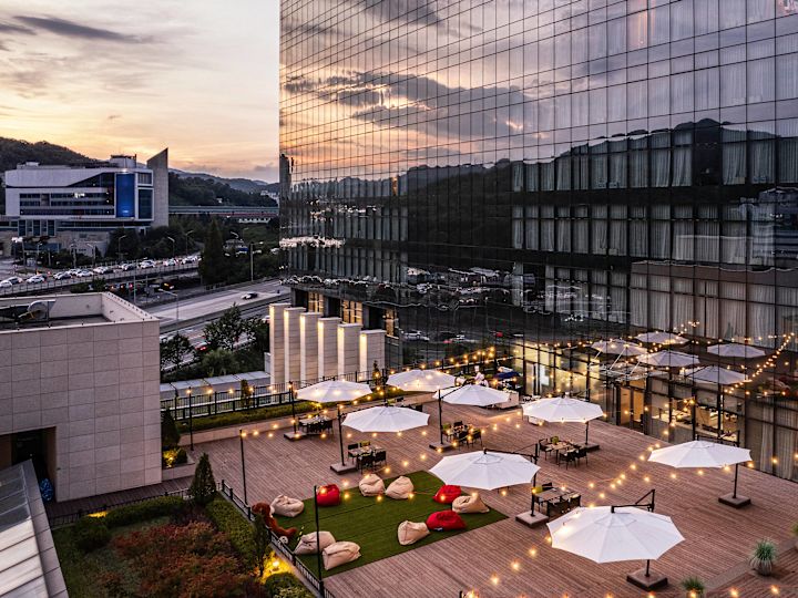 Terrasopstelling met verlichting en tafels onder parasols voor een evenement bij zonsondergang 