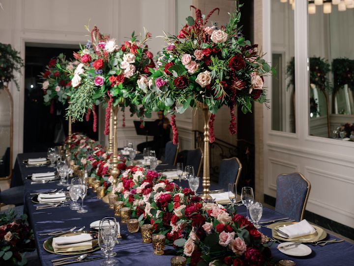 Aranjamente cu flori cu trandafiri roșii, albi și roz pe o masă pentru a sărbători o nuntă