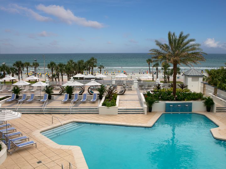 Outdoor Swimming Pool Area with Deck Chairs, Umbrellas and Ocean View