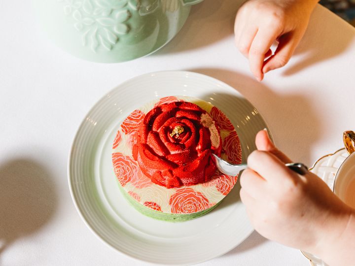 Fată care are tort în formă de trandafir într-un restaurant