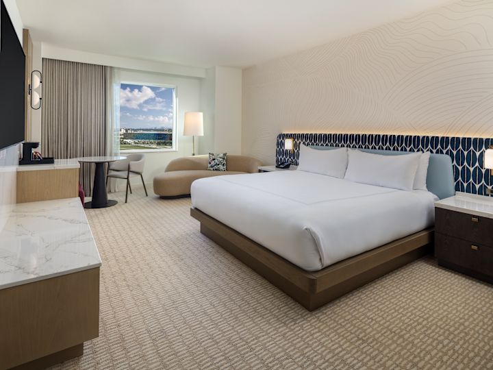 Pat mare, televizor, birou și canapea într-o cameră de oaspeți