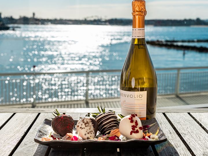 一盘巧克力草莓，海湾前露台上的一瓶葡萄酒