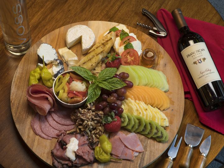 Close-Up of Various Foods on Wooden Plate and Wine Bottle