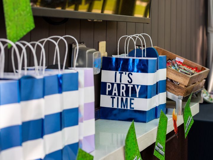 Party bags reading "It's party time!" on a table with birthday decorations.