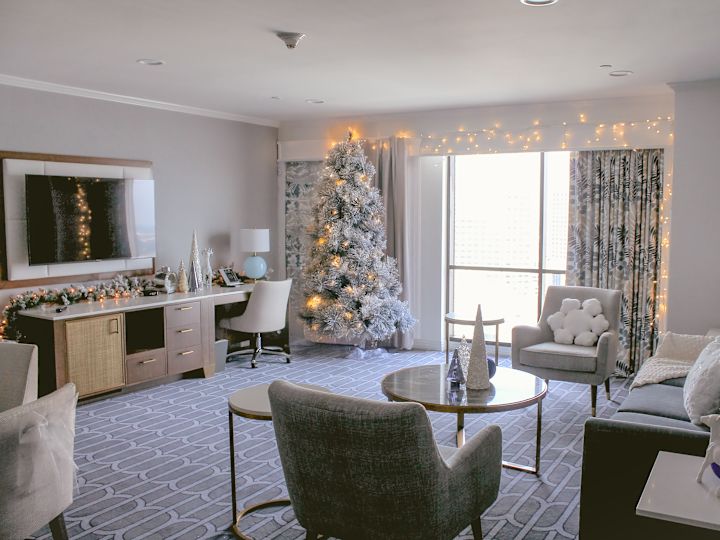 假日套房座椅，墙上有电视和带有各种圣诞装饰和灯光的柜子