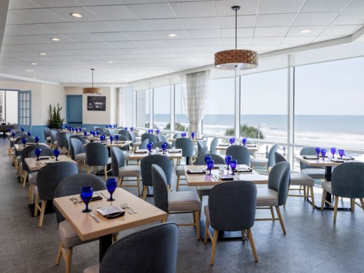 Coin repas du Café Amalfi avec vue sur la plage depuis de grandes fenêtres