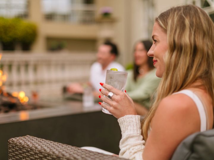 Woman holding cocktail in Torreyana Lounge with depth of field focus on here whilst couple in background are out of focus
