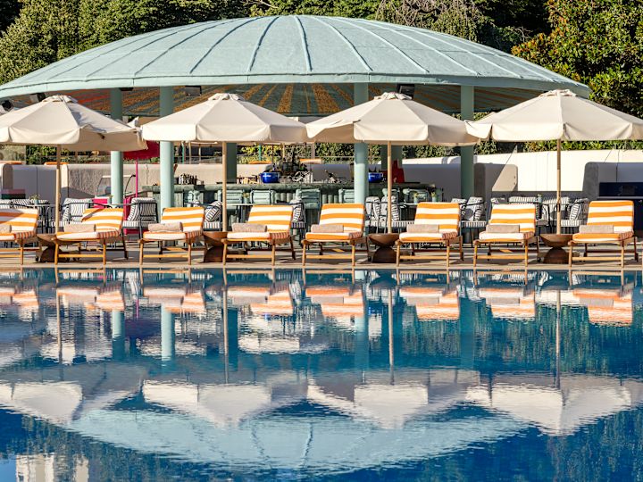 Area piscina esterna con sedie a sdraio sotto gli ombrelli