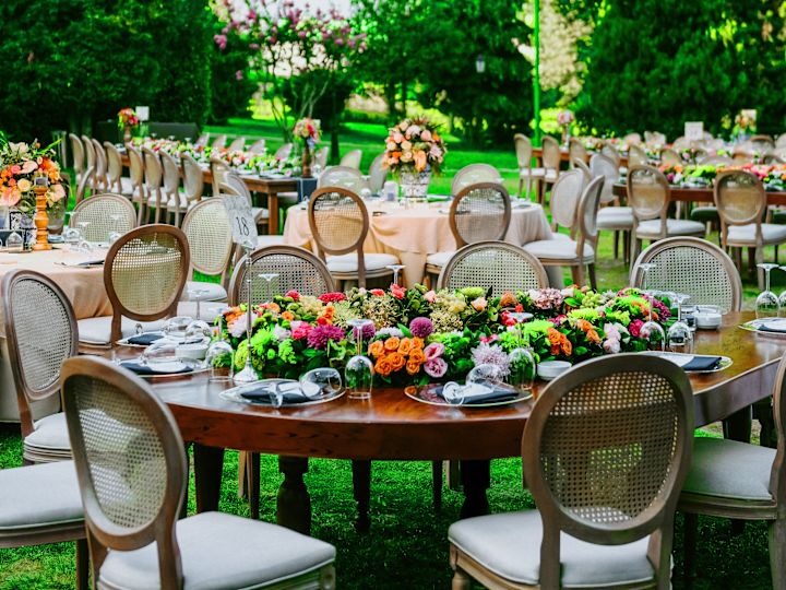 Hochzeit im Freien mit runden Tischen, Stühlen, Bäumen und Blumen