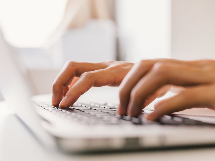 Closeup of hands typing on a laptop keyboard
