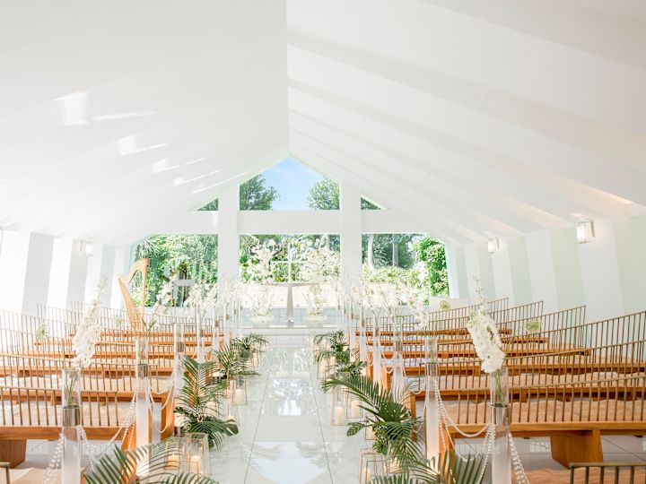 Kapell med glasvägg och naturliga träbänkar dekorerade med blommor och grönska.