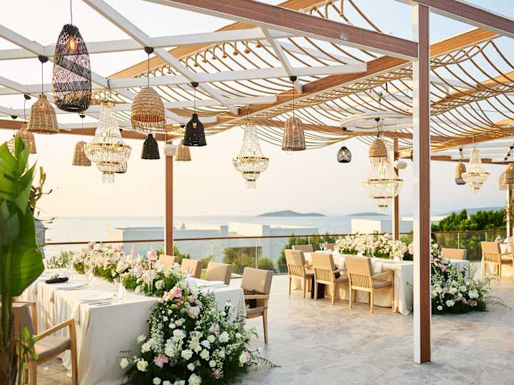 Una terrazza del ristorante con tavoli decorati con fiori e luci per celebrare un matrimonio