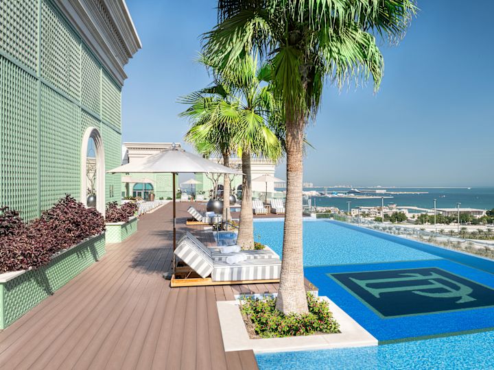 Outdoor Pool Area with Lounge Seats under Umbrellas, Palm Trees and Beach View